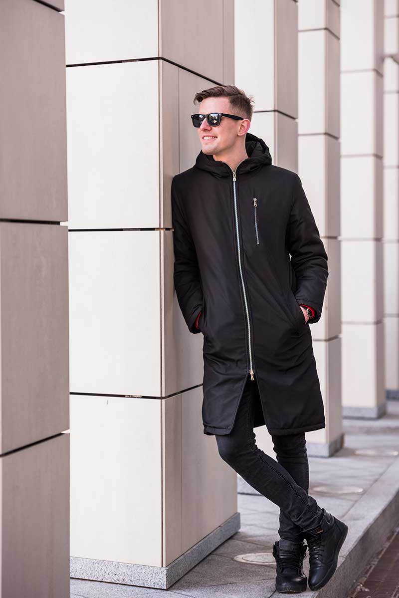 smiling-young-man-with-hands-pocket-leaning-wall